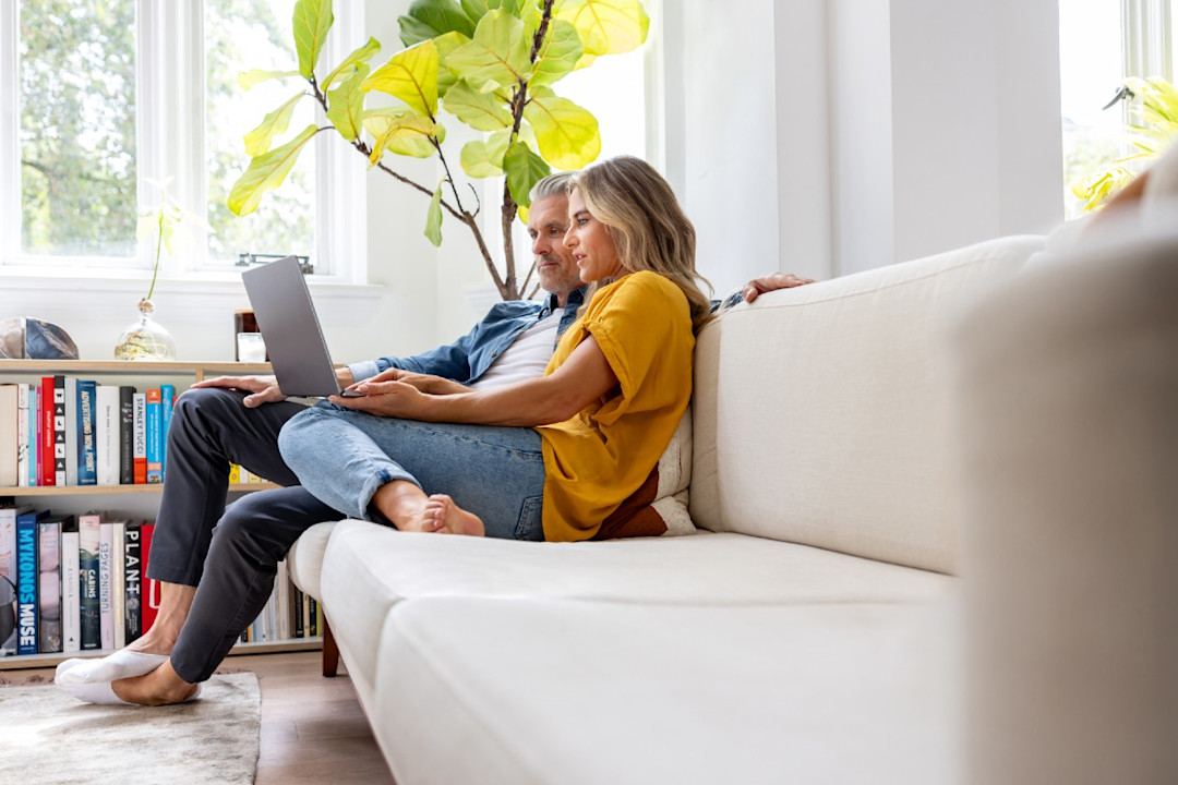 Couple doing research on their laptop together on the sofa.jpg