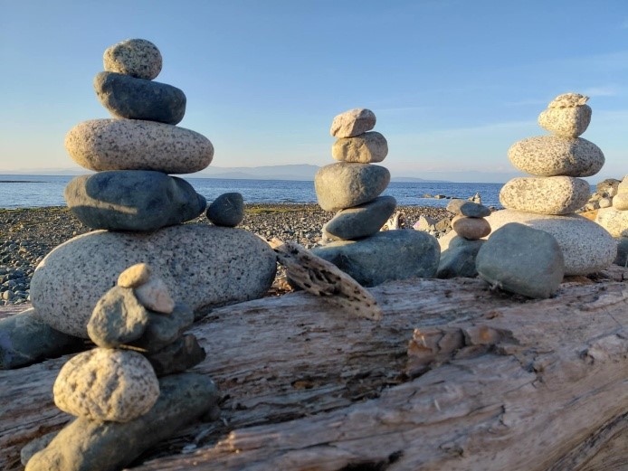 At the beach in Victoria with a selection of carefully balanced stones on a weathered log