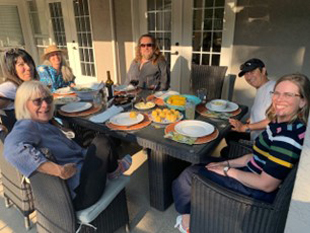 In-person Fundamentals of Visual Coaching class: Students gathered around the lunch table smiling at the camera.