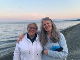 Christina Merkley on the beach in Metchosin BC, as the sun sets behind created a beautiful pinky-peach sky.
